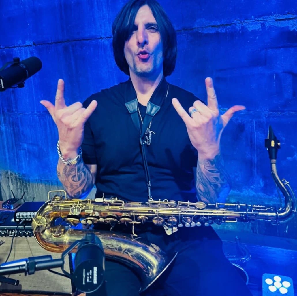 Greg Capozzi with his saxophones under blue stage light at a private party