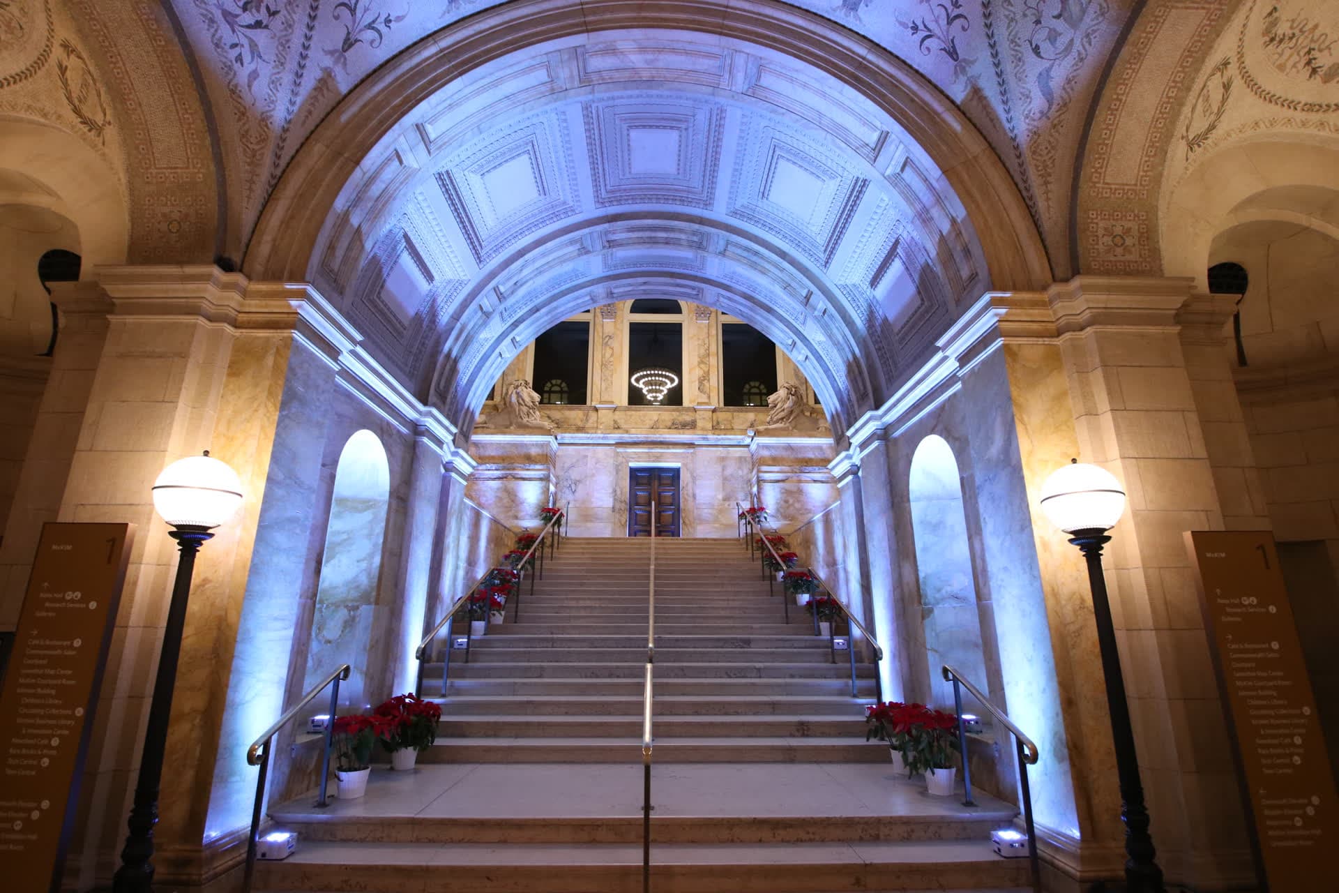 The Boston Public Library's McKim entrance staircase in lavender uplighting, with the stone lions on the landing