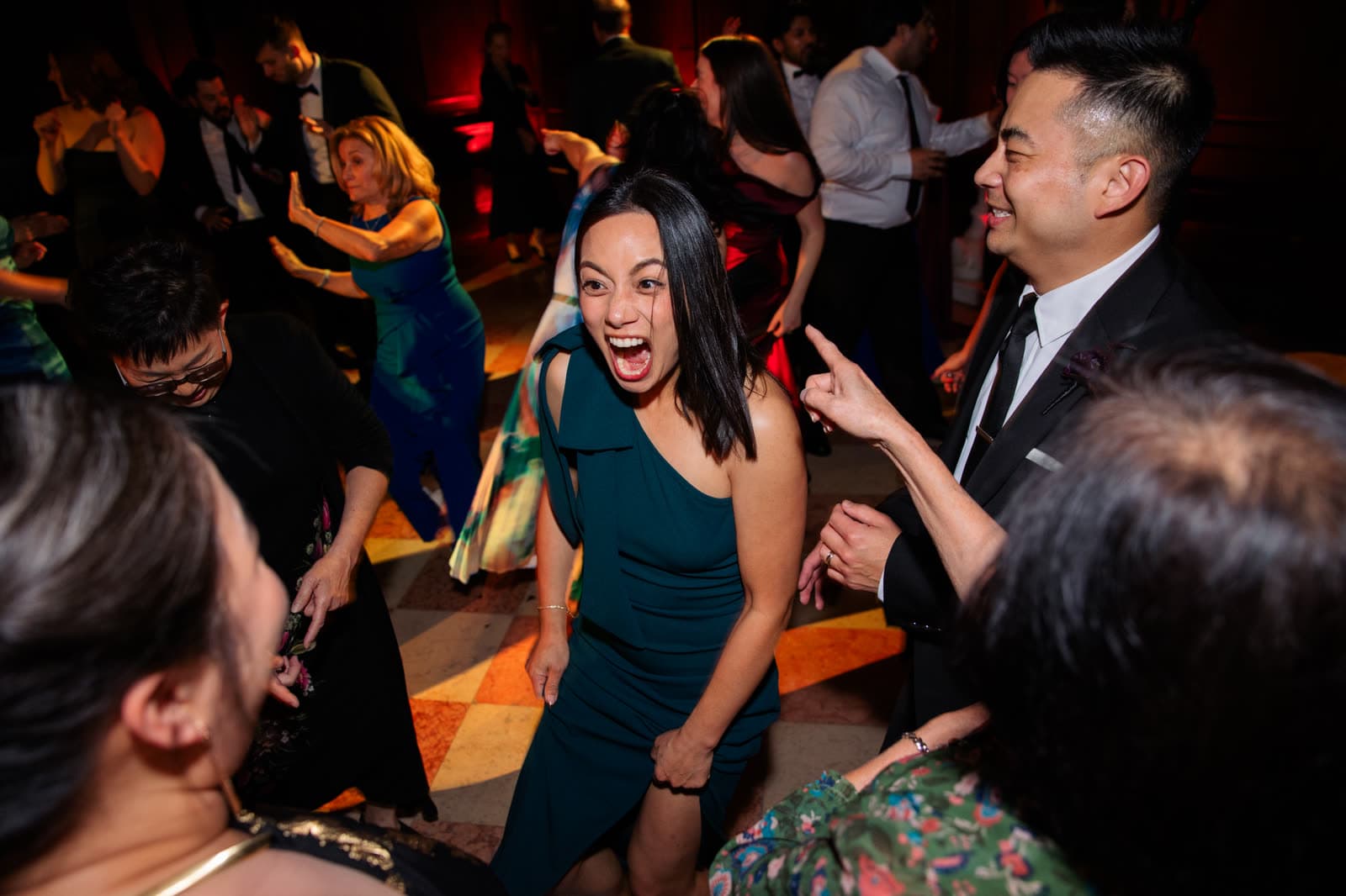 Guests in cocktail attire mid-song on a warmly uplit ballroom dance floor