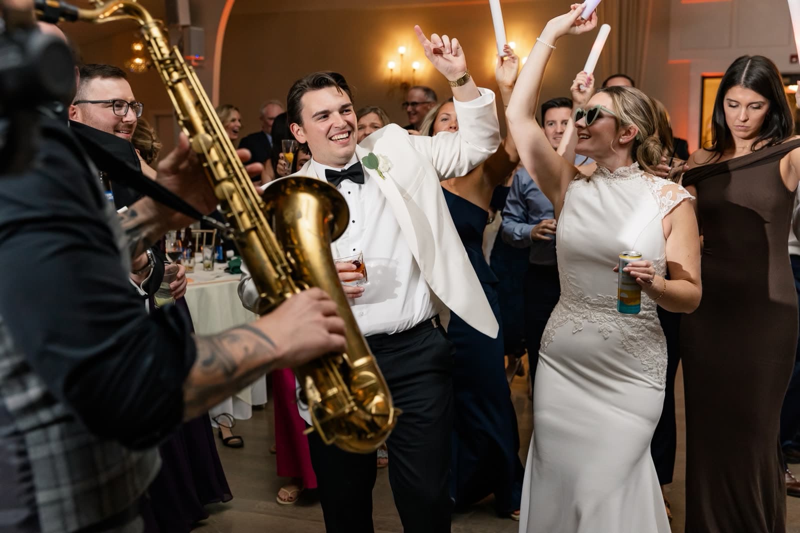Saxophonist in the middle of a packed wedding dance floor beside the groom