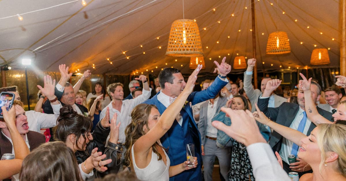 A packed dance floor under a sailcloth wedding tent