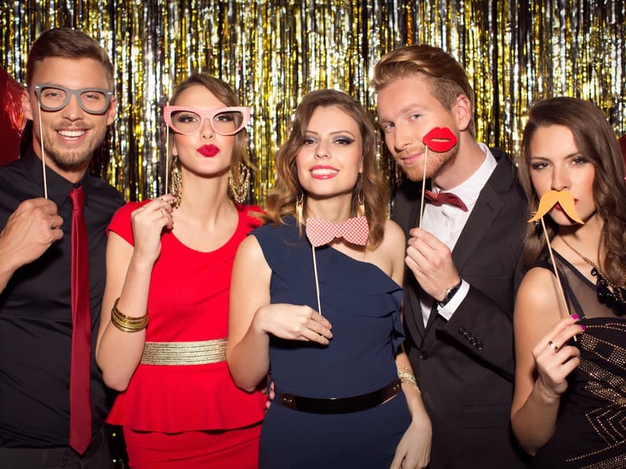 Five guests posing with props in front of a gold sequin backdrop