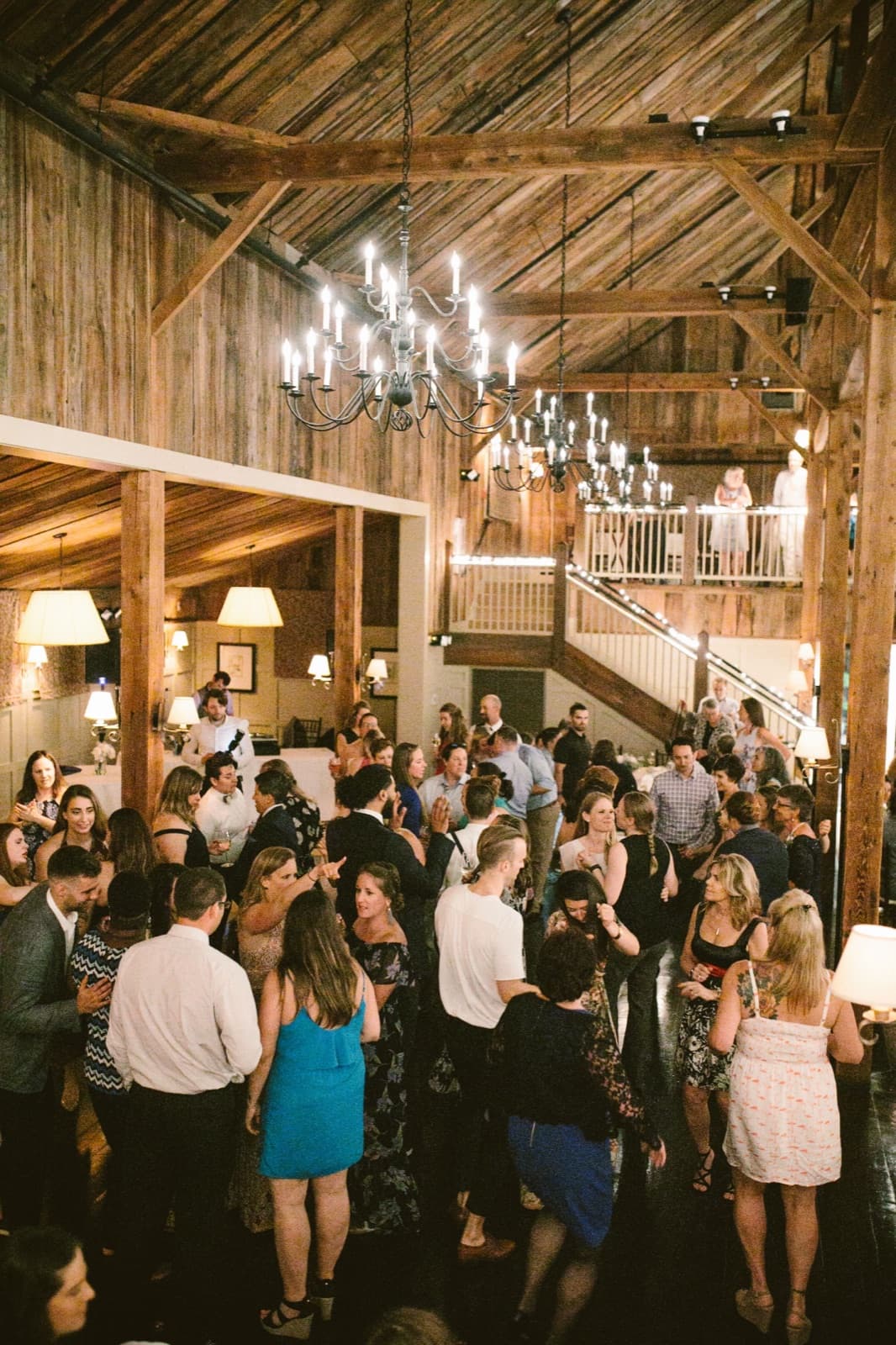 A packed dance floor under the chandeliers at The Barn at Gibbet Hill, seen from the loft