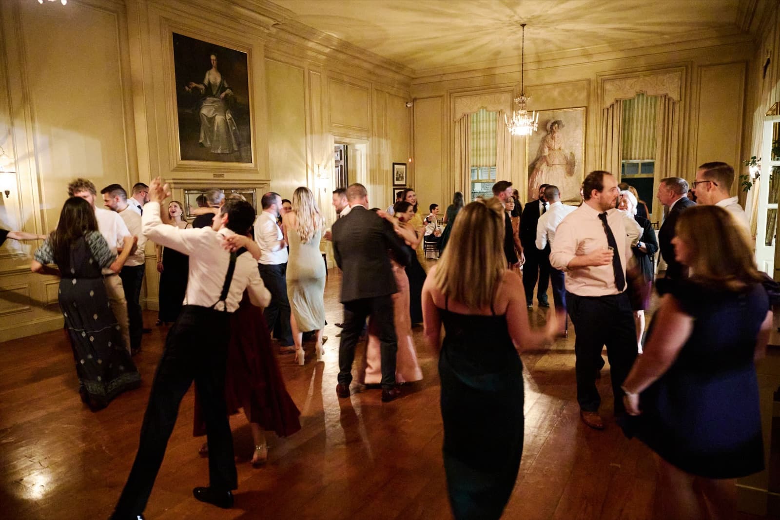 The Crane Estate ballroom under its chandeliers without uplighting, guests dancing on the wood floor