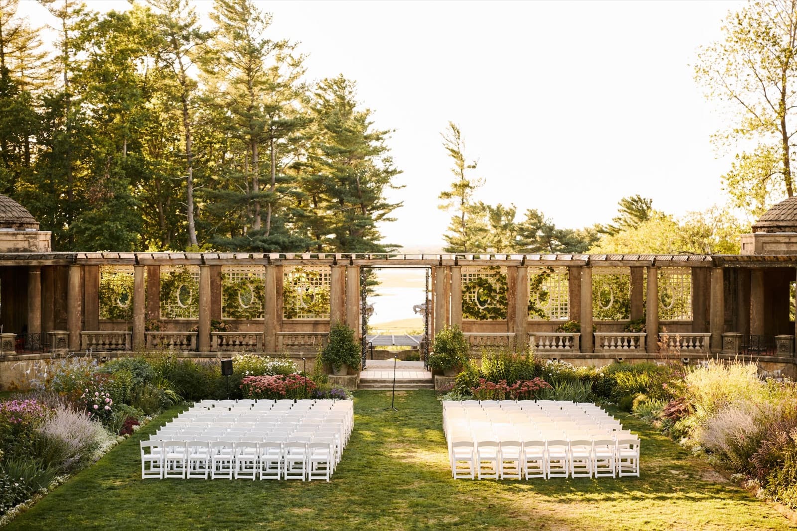 Ceremony chairs set in the Italian Garden at the Crane Estate, facing the pergola in late sun