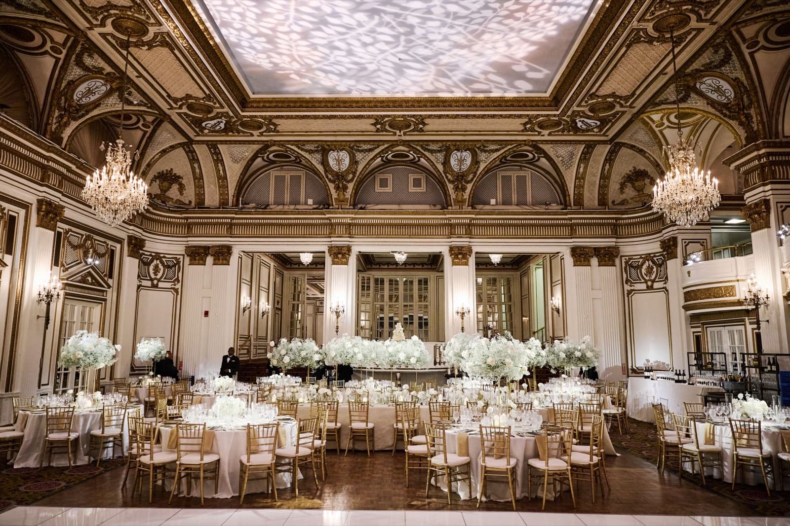 The Grand Ballroom at the Fairmont Copley Plaza set for a wedding dinner under gilded arches and crystal chandeliers