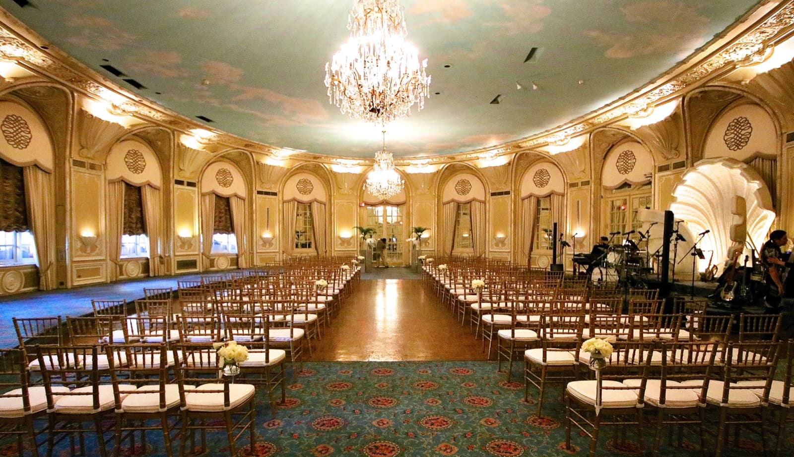 The Oval Room at the Fairmont Copley Plaza set for a ceremony, rows of gold chairs on either side of an aisle under a crystal chandelier