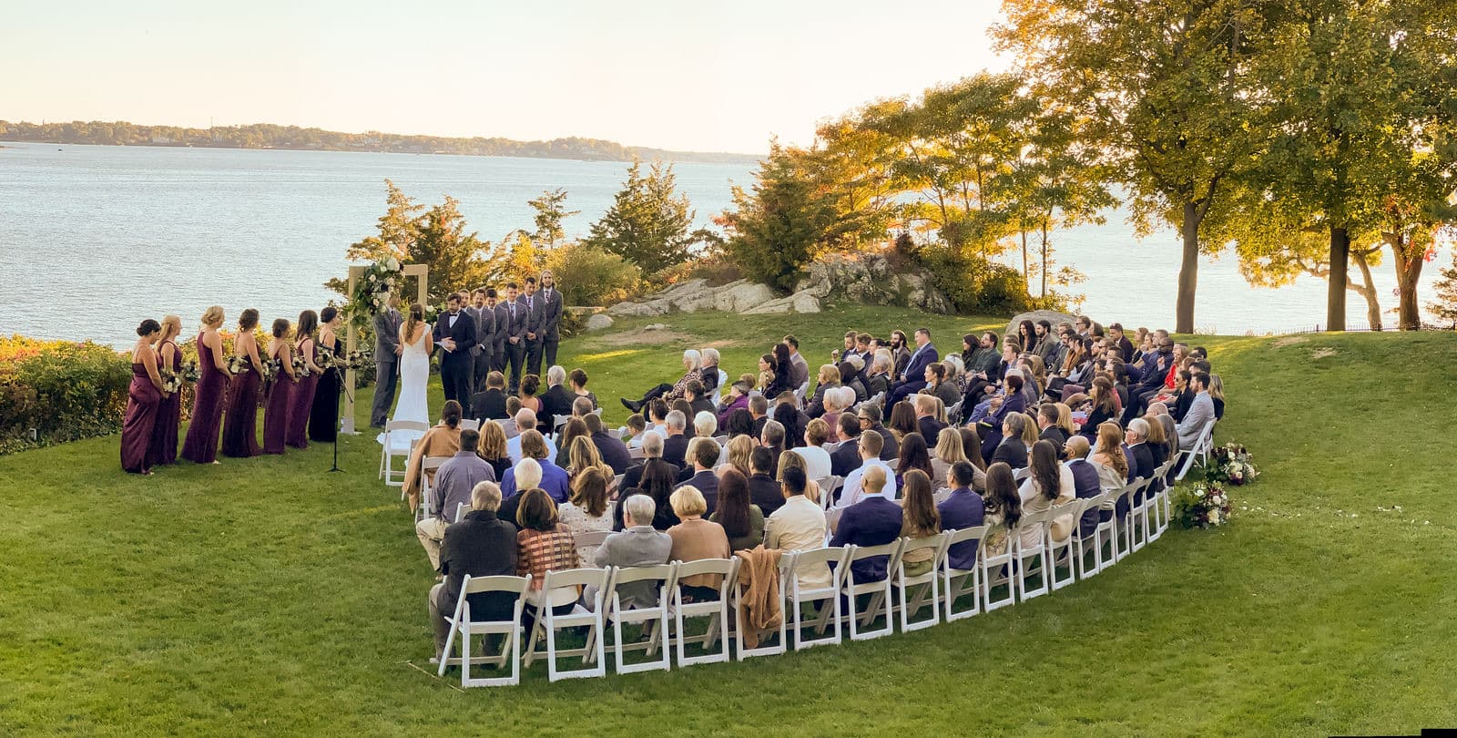 A Misselwood ceremony from above the back rows, the chairs curved toward the arch and the ocean beyond