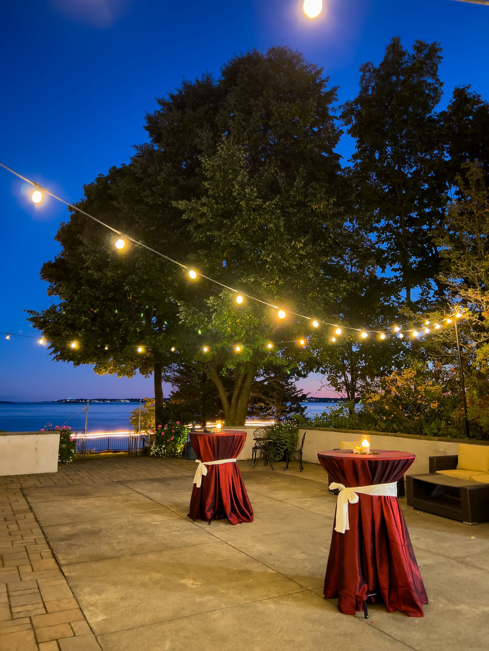 The Misselwood cocktail courtyard at dusk with string lights, high-top tables and the ocean beyond