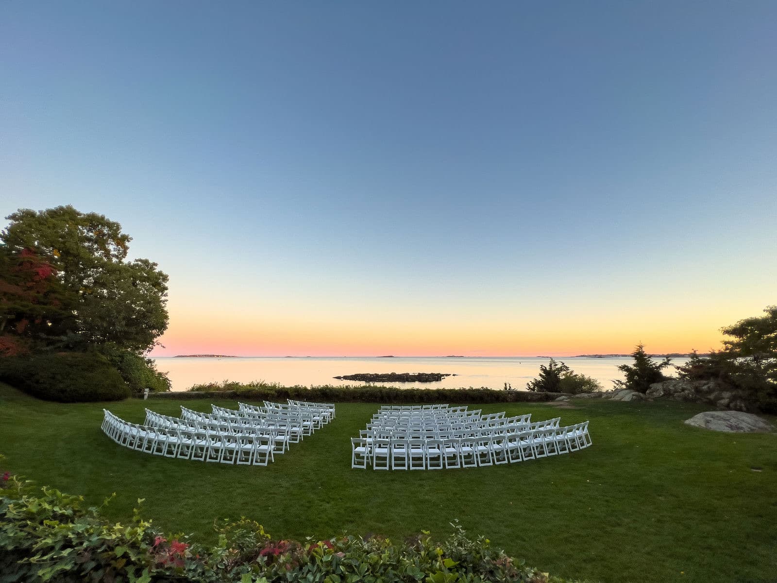 Empty ceremony chairs on the Misselwood lawn at dusk with the ocean behind