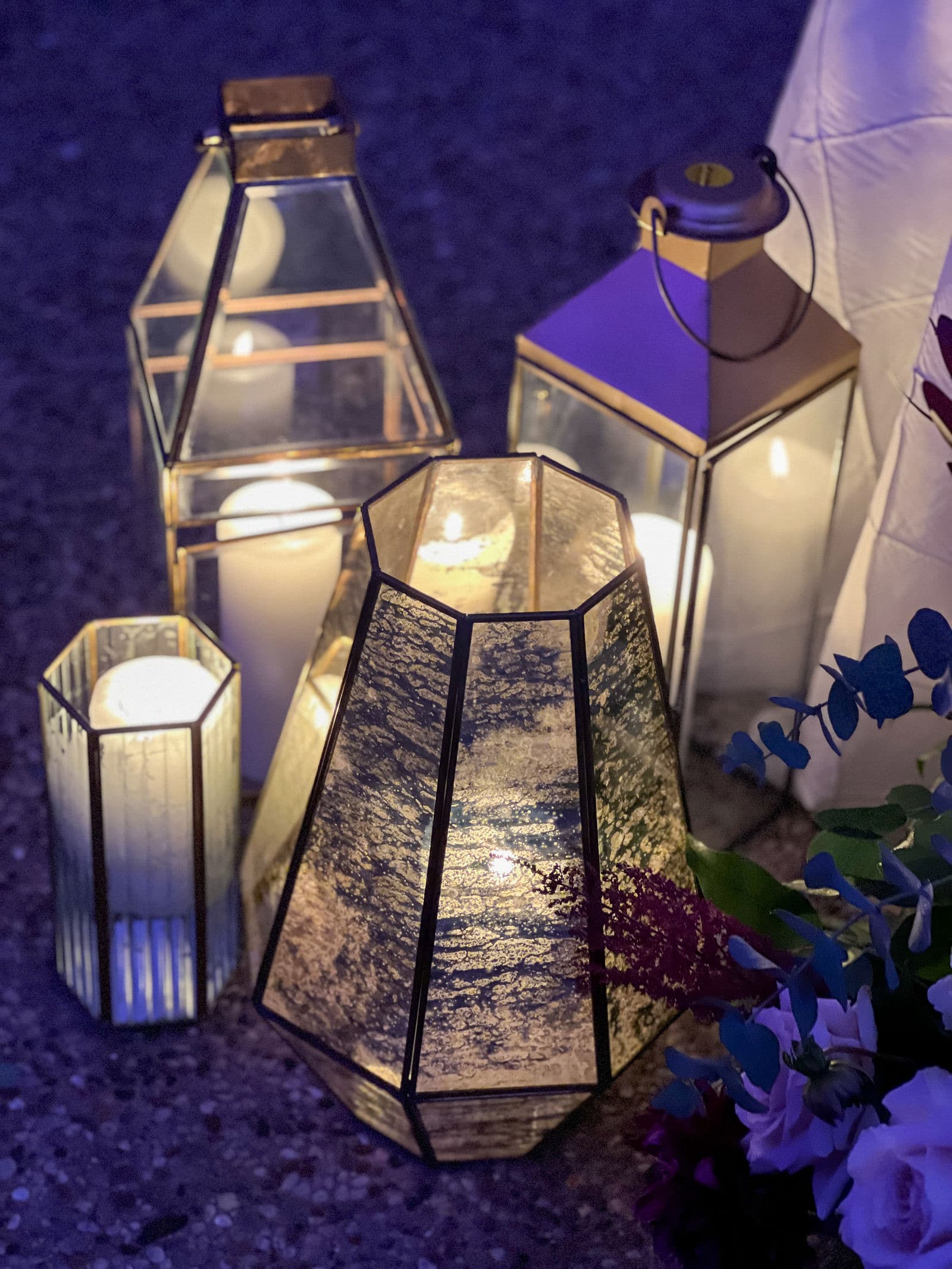 Lanterns on a table with the lit tent behind them