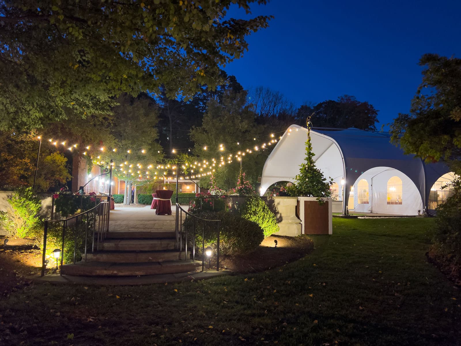 The Misselwood tent lit from inside at night with a string-lit path leading down to it