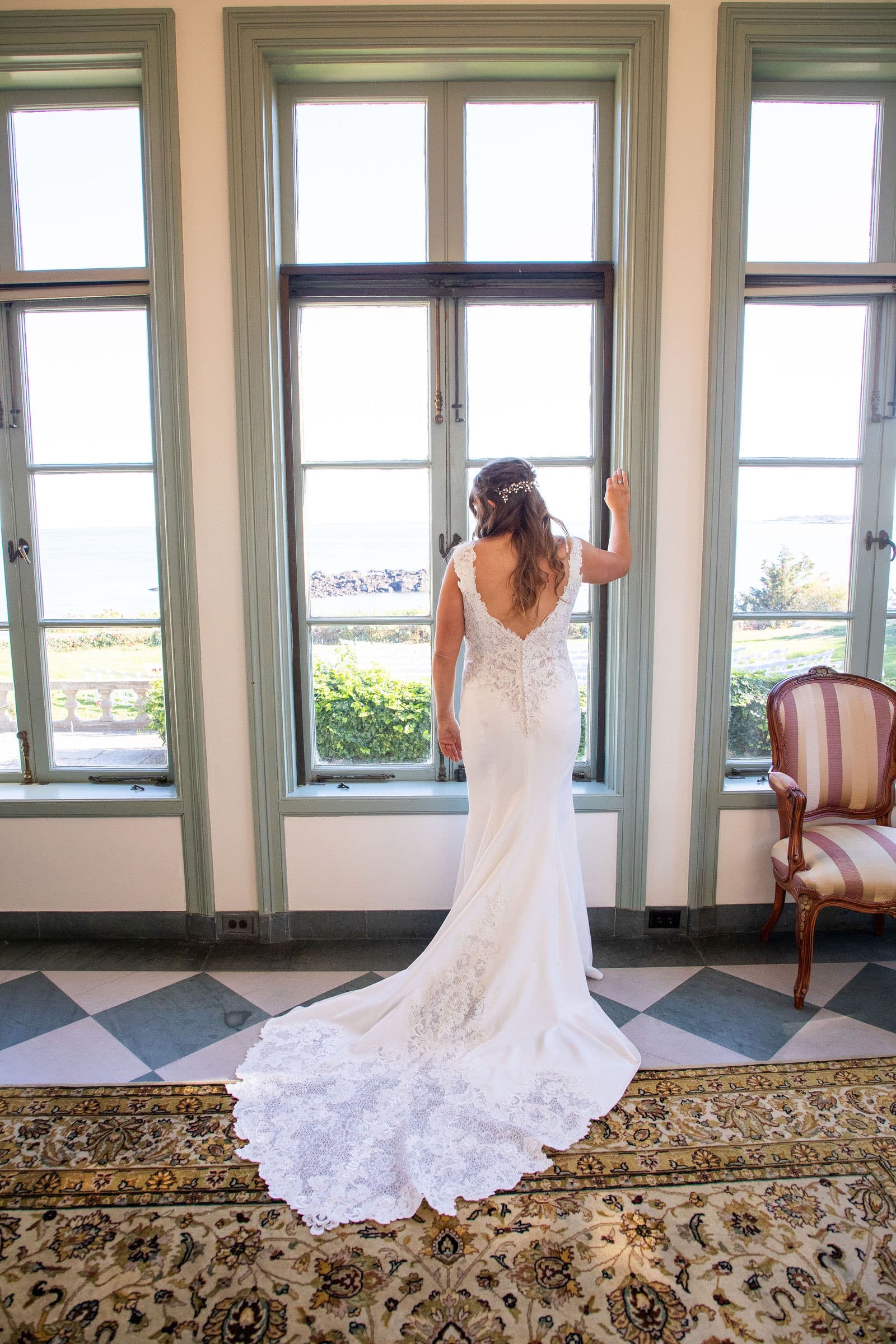 A bride at the tall windows of a Misselwood sitting room, the water visible outside