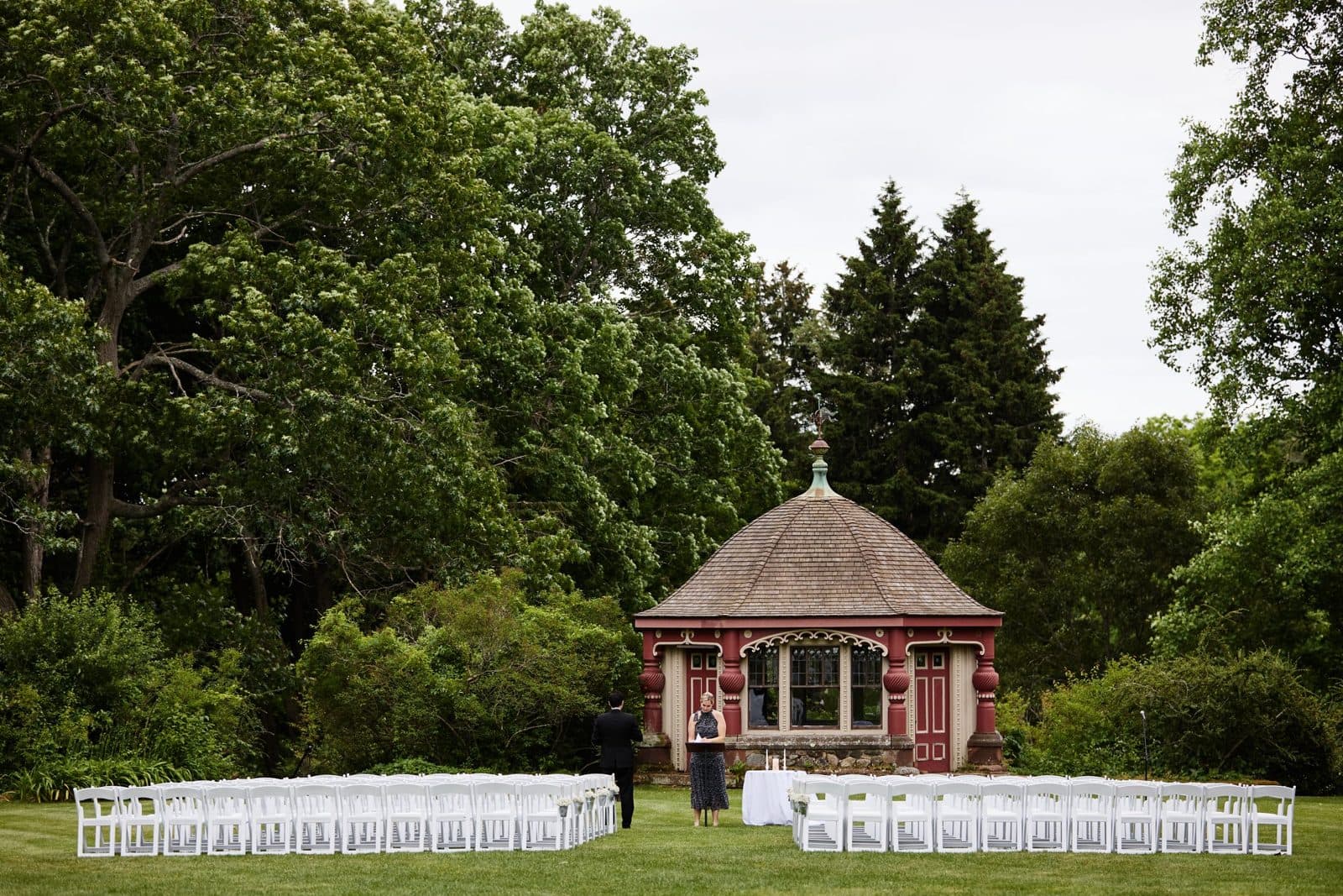 White ceremony chairs set on the field in front of the tea house at Moraine Farm