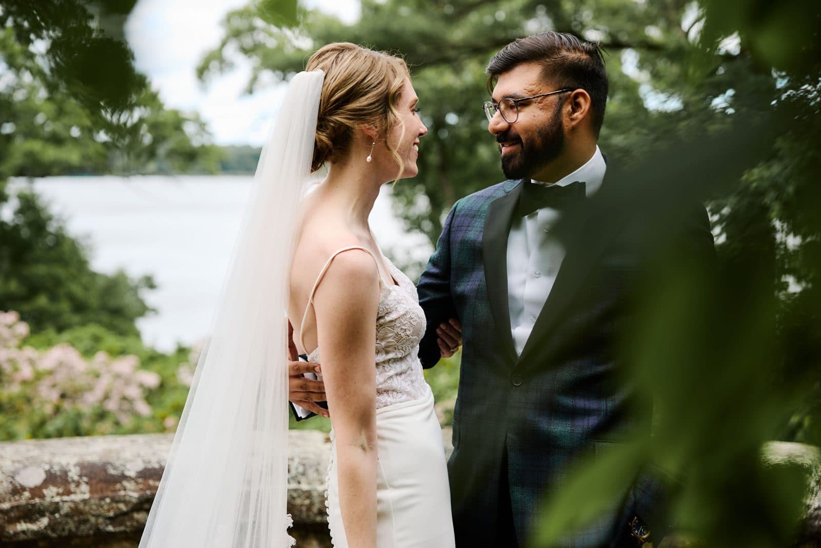 A couple beside the low fieldstone wall at Moraine Farm, Wenham Lake behind them