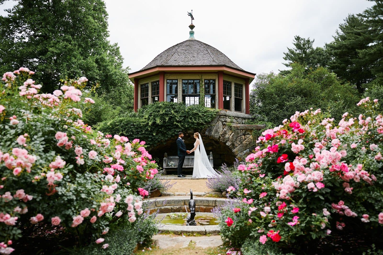 The historic tea house at Moraine Farm framed by pink and red roses