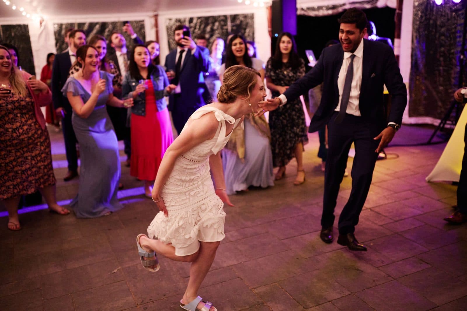 Guests dancing in the tent at Moraine Farm under purple uplighting