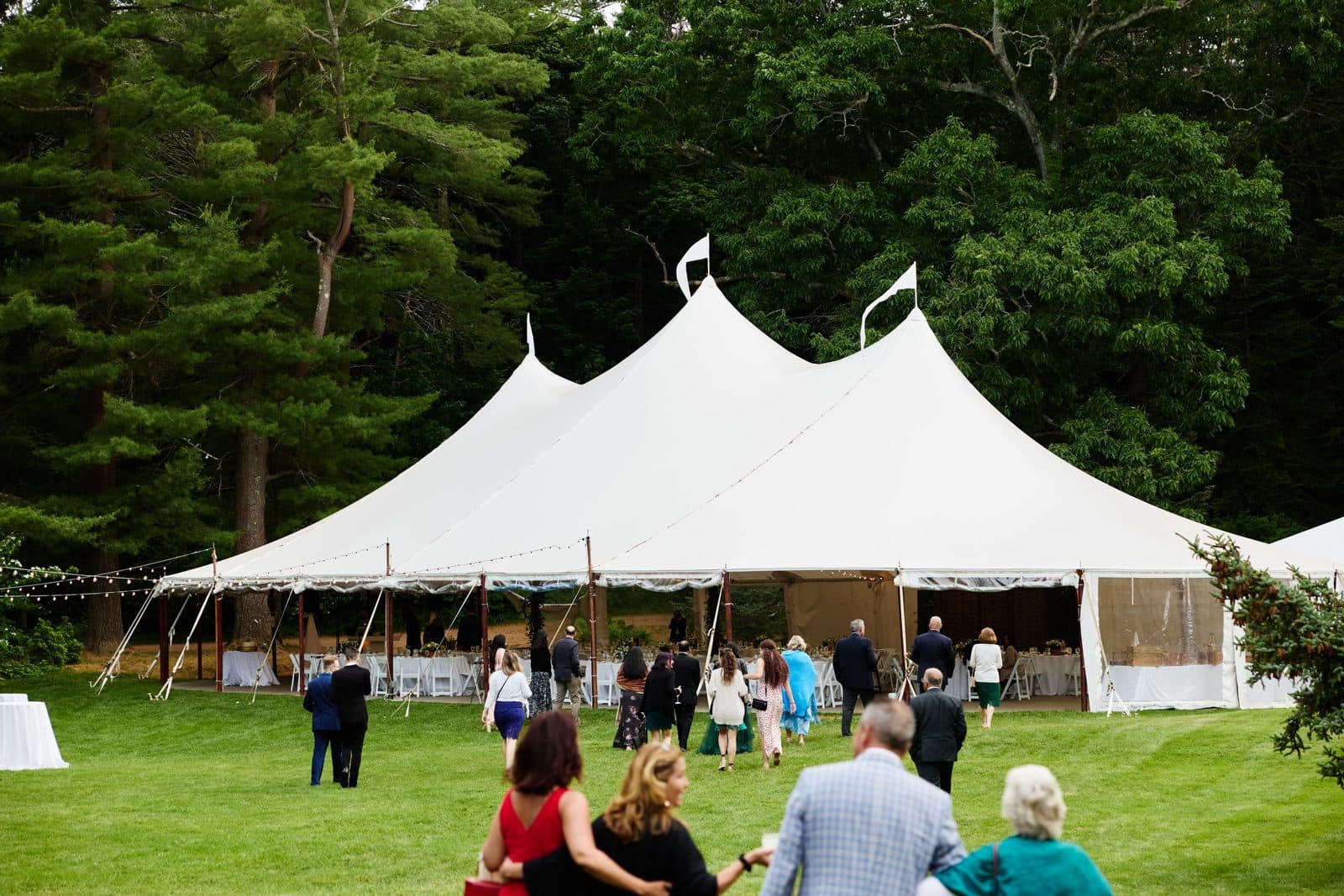 White peaked tents on the lower lawn at Moraine Farm, guests walking down toward them