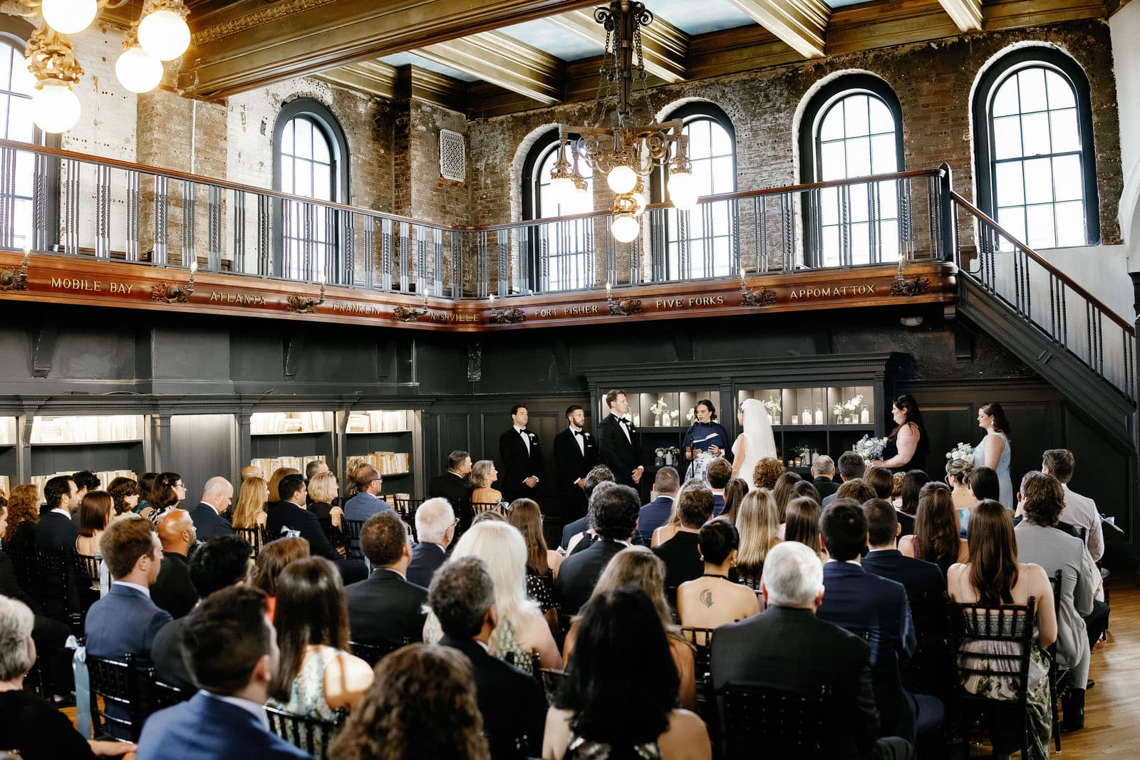 A wedding ceremony at The Tower in Boston seen from the balcony, guests seated under the chandelier