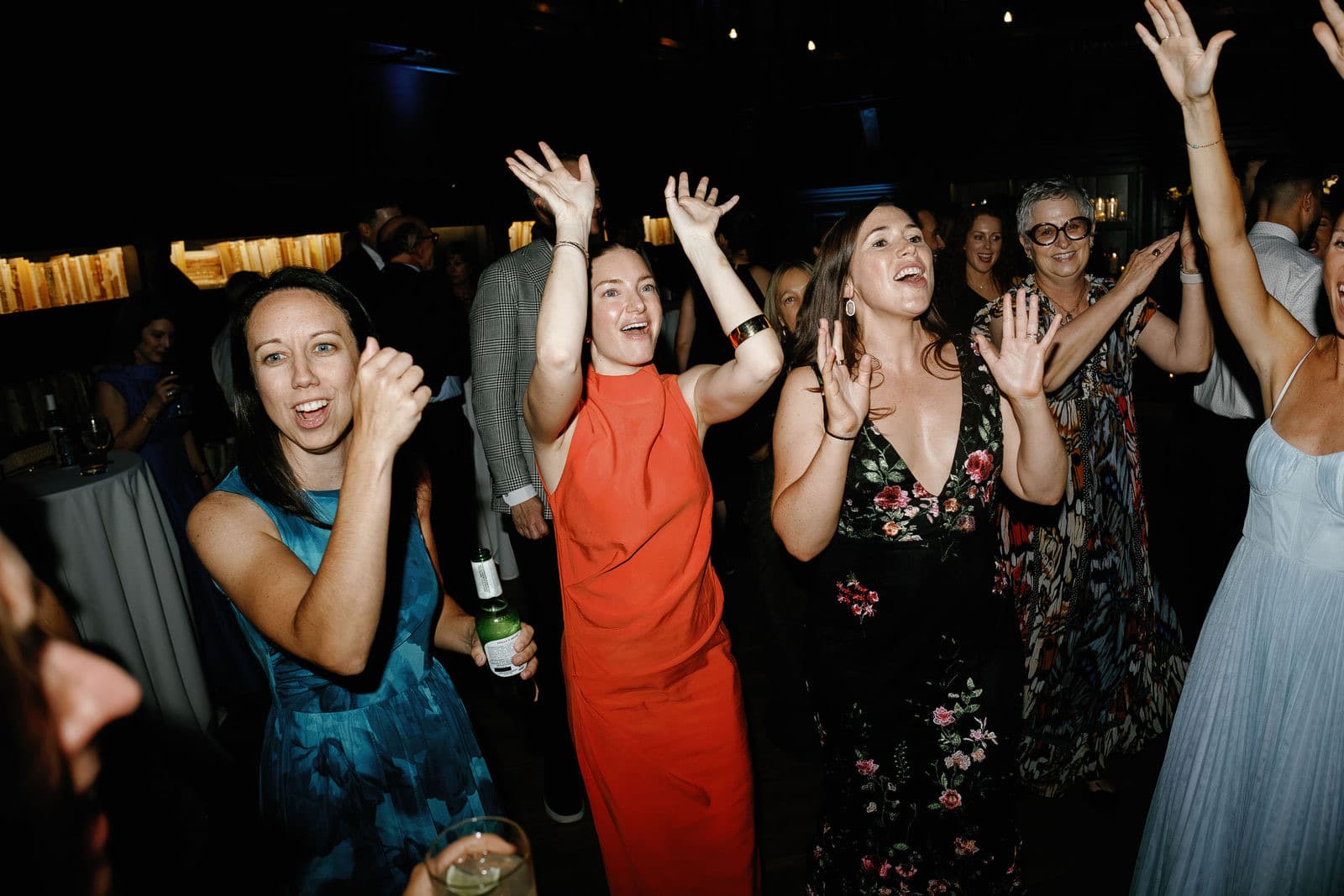 Guests dancing at The Tower with their hands up and teal uplighting behind them