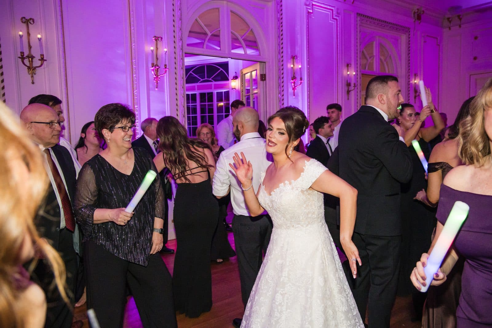 A packed Tupper Manor ballroom in purple uplighting during the dance set