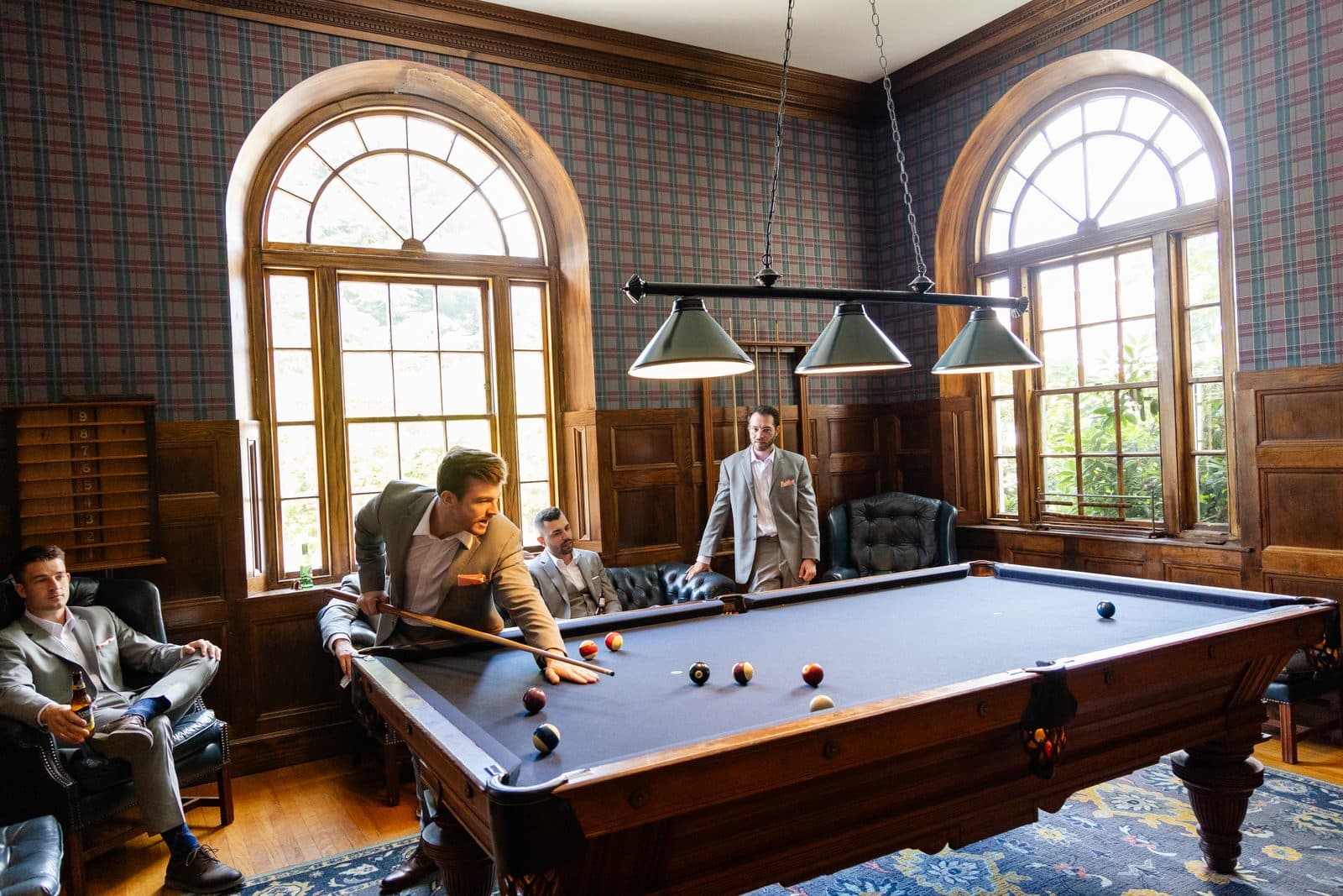 Groomsmen shooting pool in the panelled billiards room at Tupper Manor
