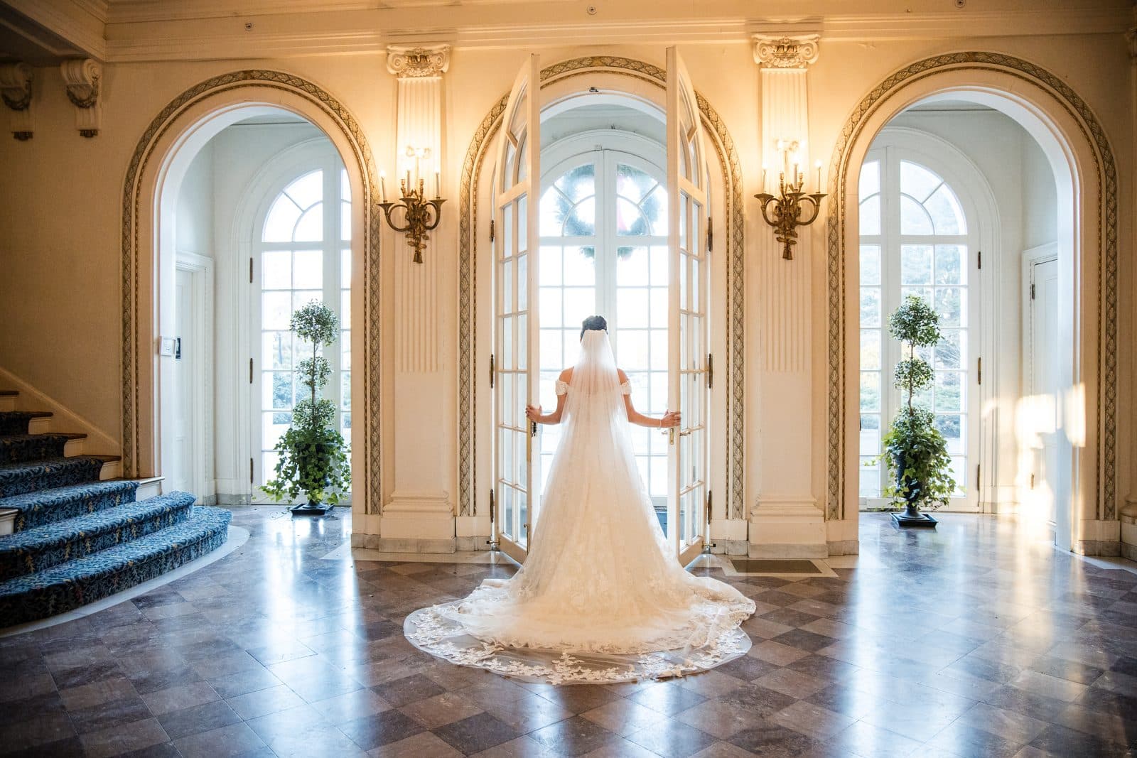 A bride in the marble foyer of Tupper Manor between the arched doors