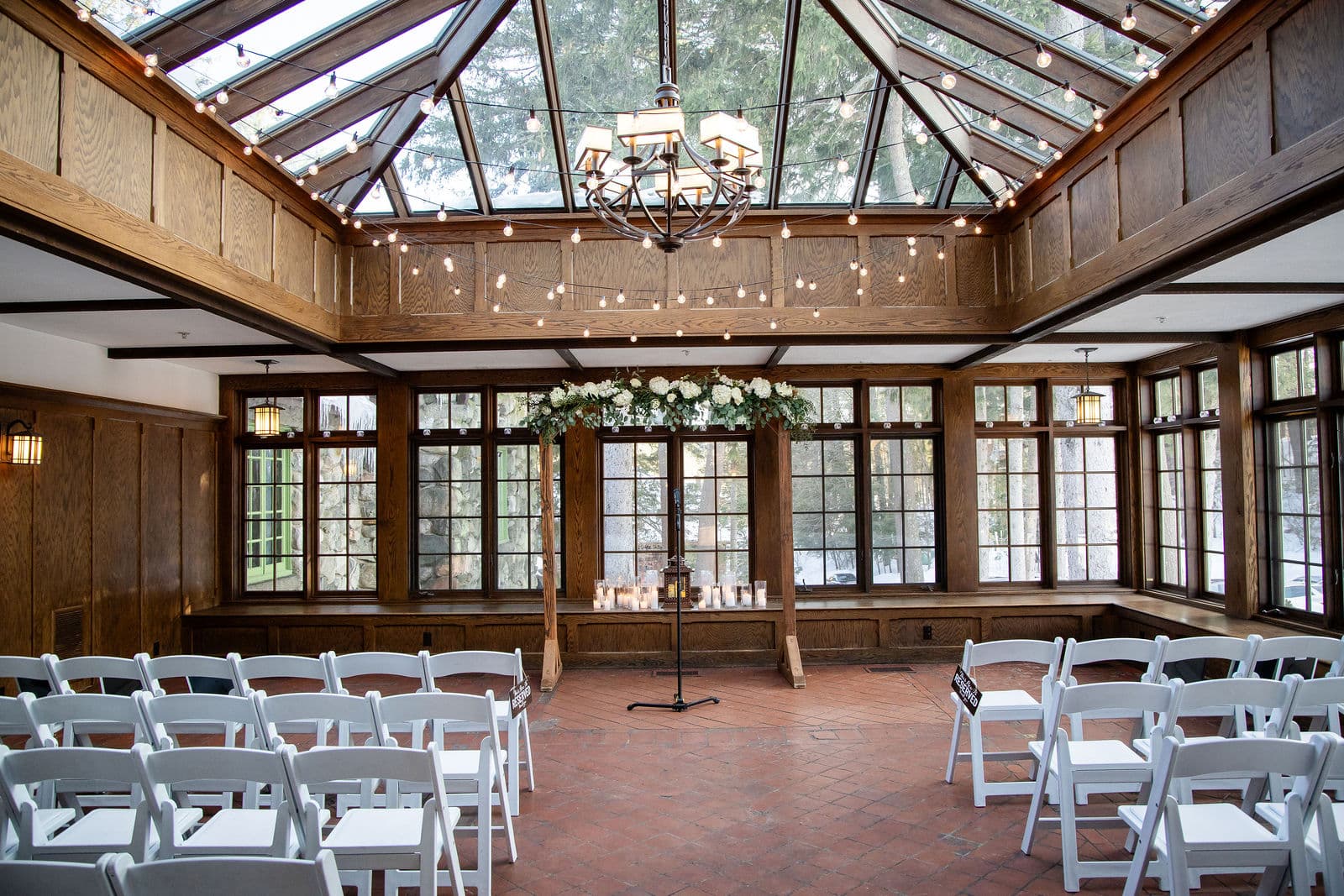 The Willowdale Estate conservatory set for a ceremony, white chairs under the glass roof and string lights