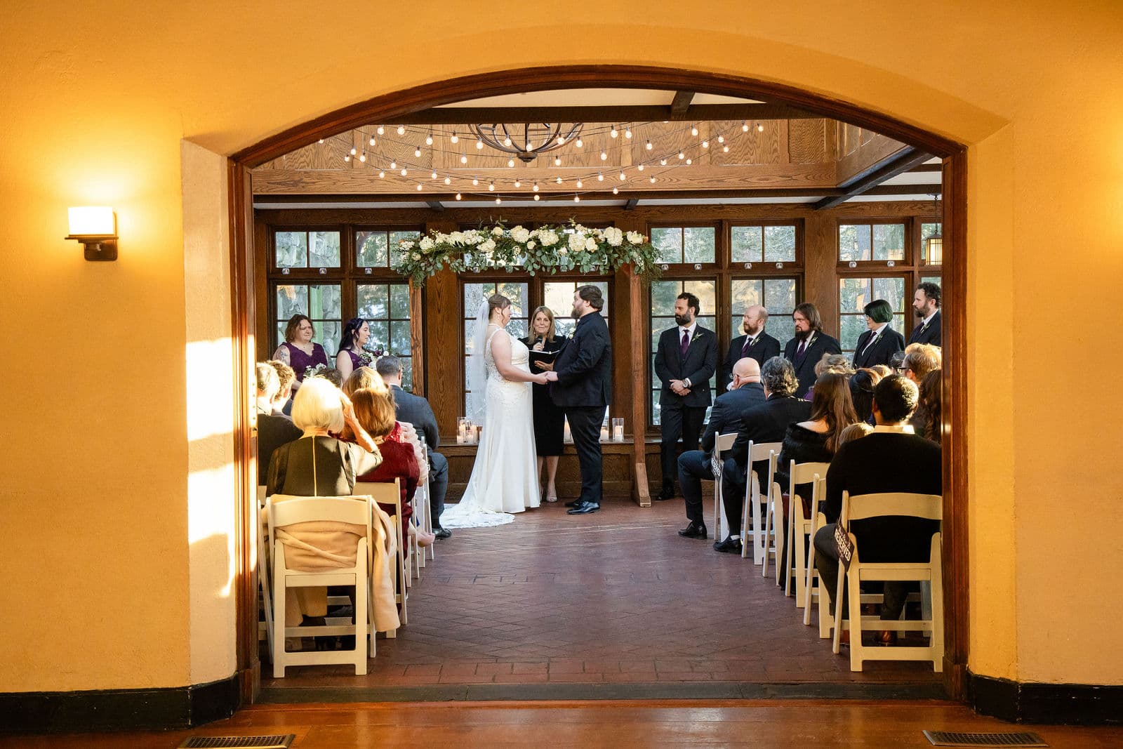 A winter ceremony in the Willowdale Estate conservatory, seen through the arch from the next room
