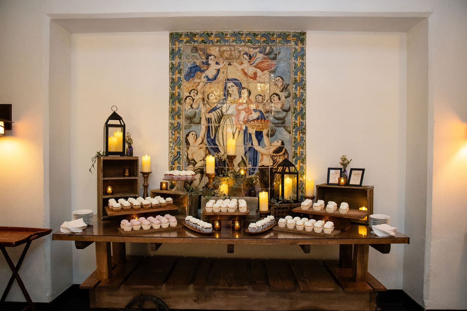 A dessert table set by candlelight under the painted tile mural at Willowdale Estate