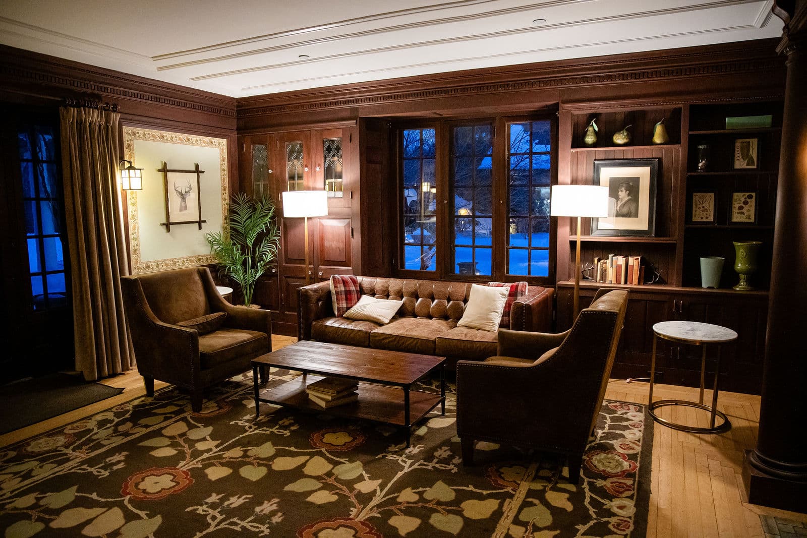 The library lounge at Willowdale Estate with leather sofas and a lit window at dusk