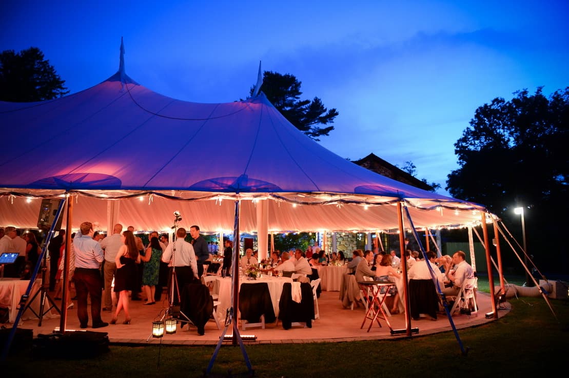 Guests dancing inside the Willowdale Estate tent in warm uplighting as the sky goes dark