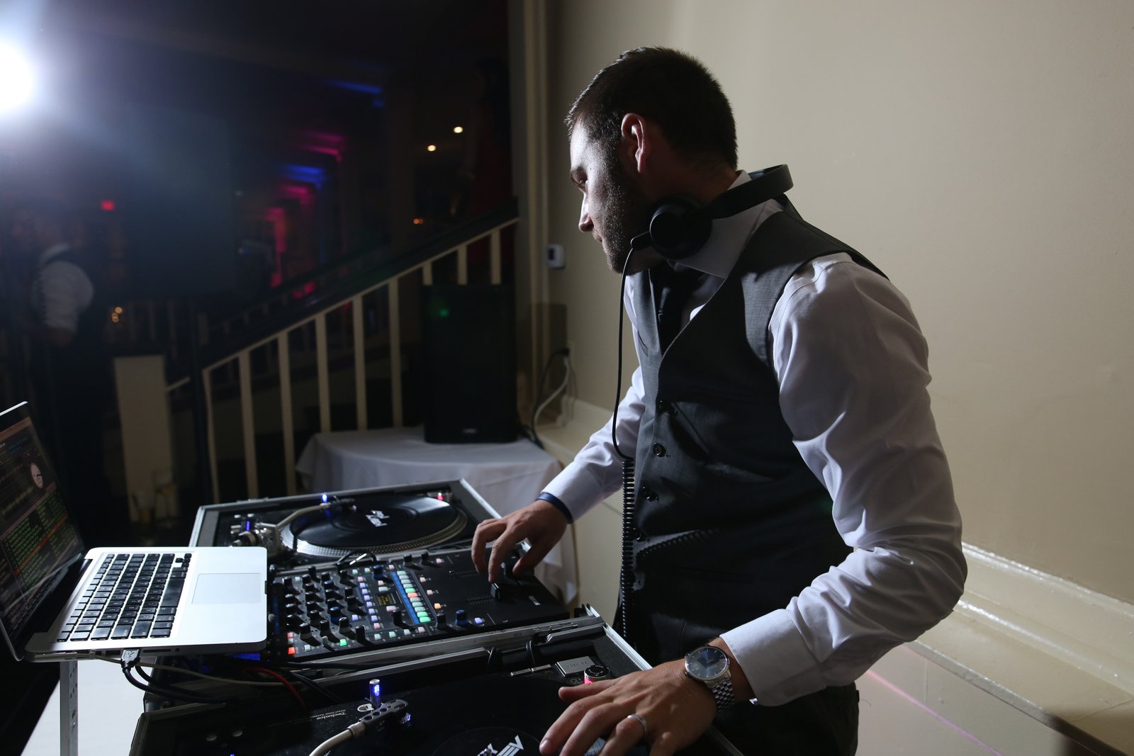 A C-Zone DJ working the mixer and turntables with a laptop on a stand beside the decks